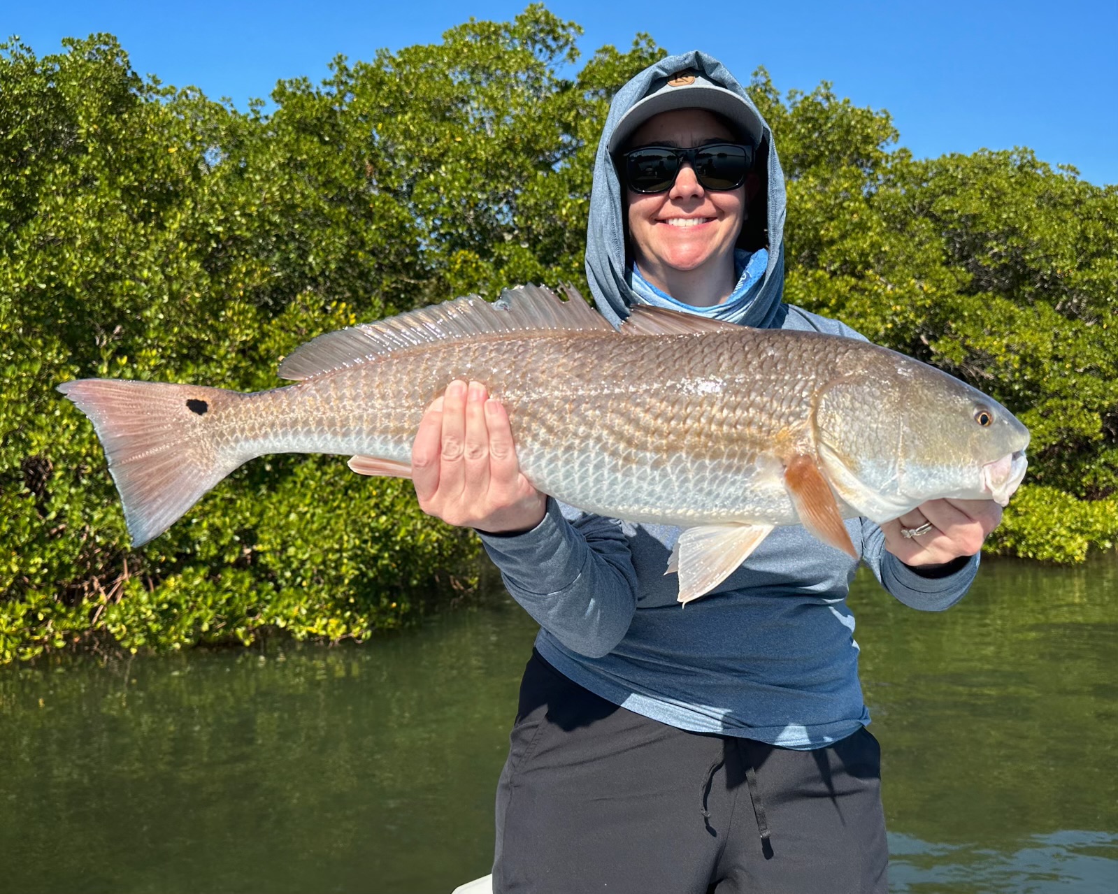 A young woman proudly displaying a freshly caught redfish during an inshore fishing adventure.