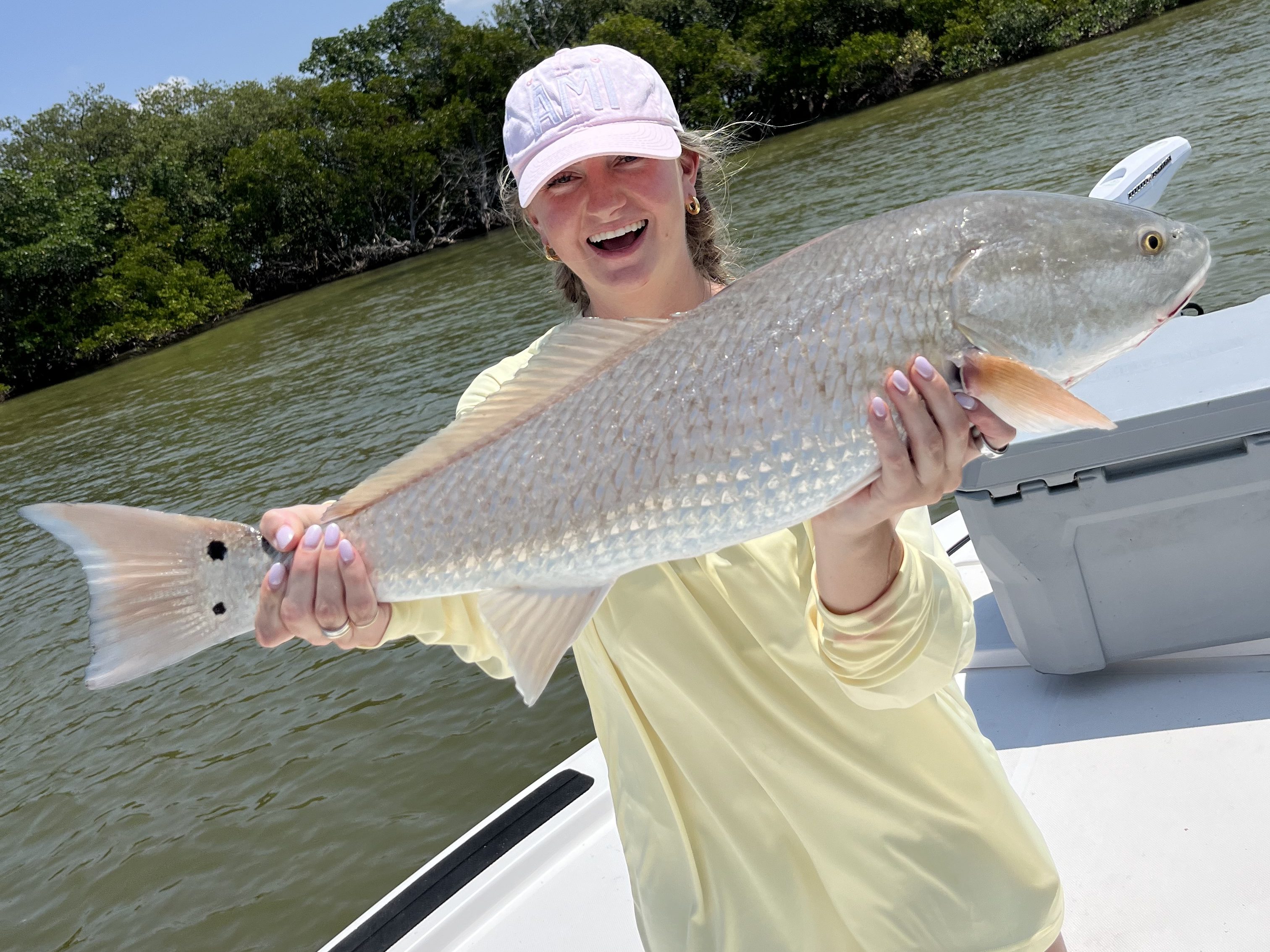 A young girl proudly displaying a freshly caught redfish during an inshore fishing adventure with Beyond Fishing Charters in Tampa Bay.